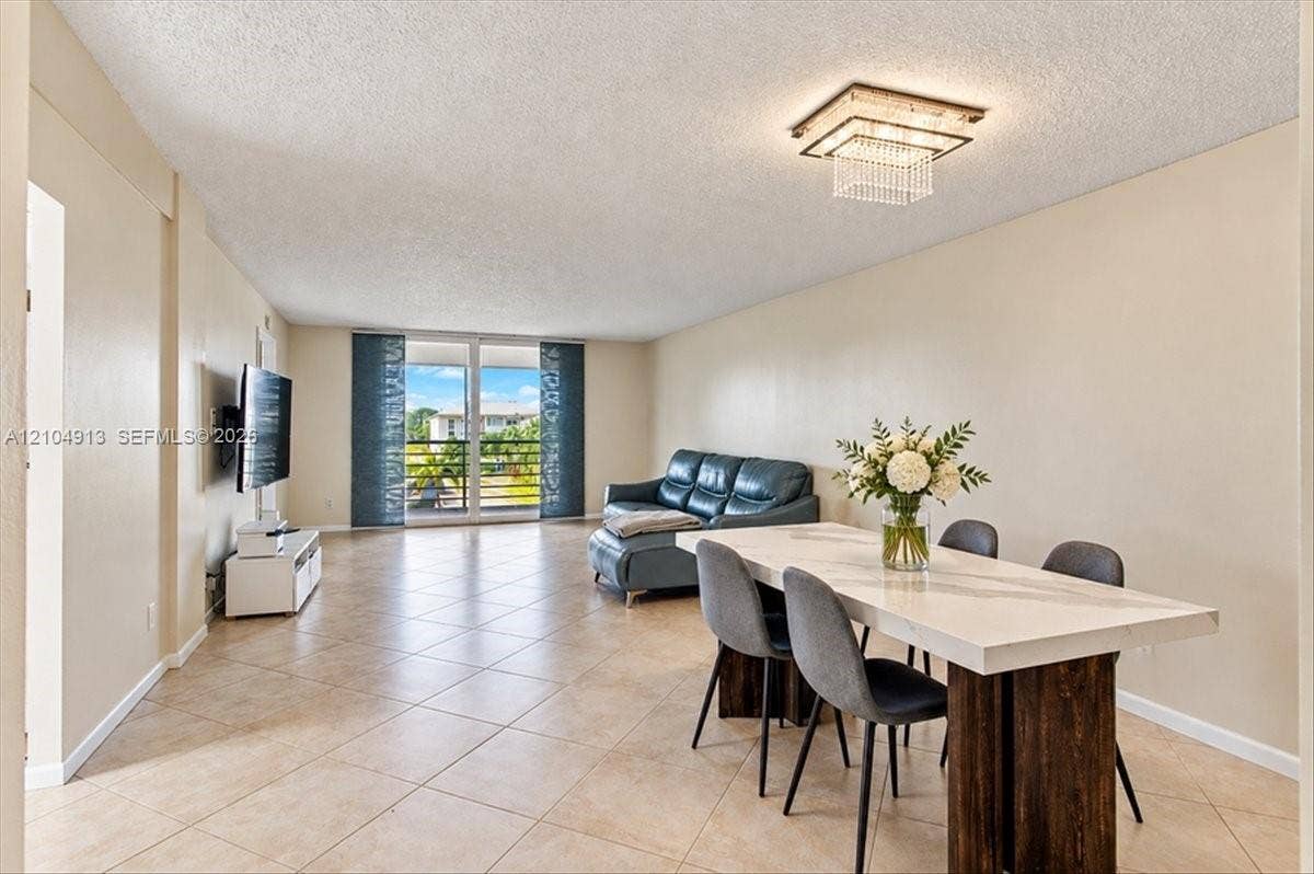 501 E Dania Beach Boulevard, #5-4A, Dania, Dania Beach, FL 33004 Neutral-toned ceramic tile flooring, tiered crystal flush-mount light fixture, and floor-to-ceiling glass sliding doors leading to an exterior balcony