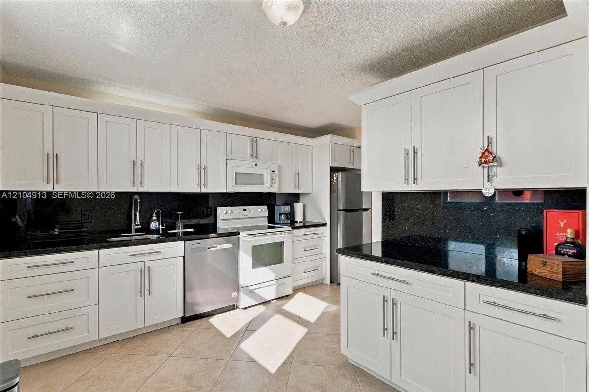 501 E Dania Beach Boulevard, #5-4A, Dania, Dania Beach, FL 33004 Kitchen featuring white shaker-style cabinetry, dark stone countertops, tile flooring, and stainless steel appliances