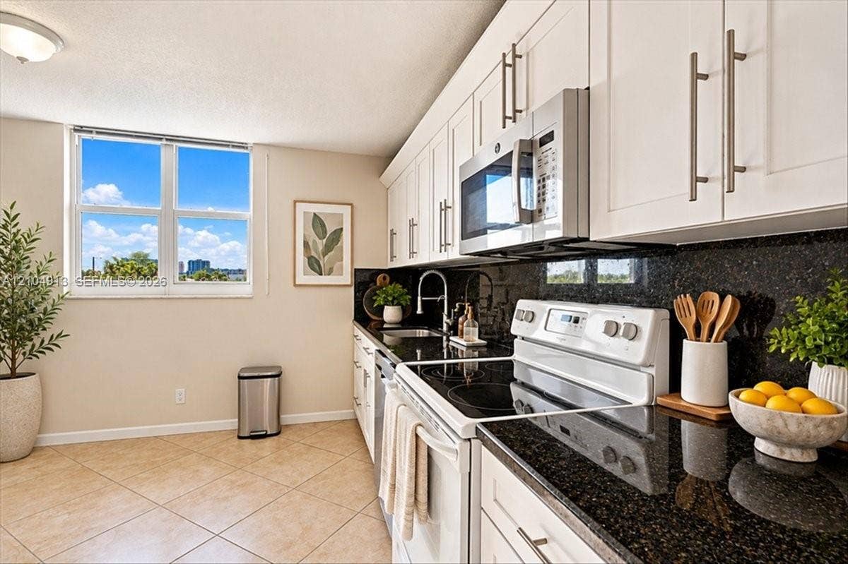 501 E Dania Beach Boulevard, #5-4A, Dania, Dania Beach, FL 33004 Kitchen featuring white shaker-style cabinetry, dark stone countertops, tile flooring, built-in stainless steel microwave, and white range