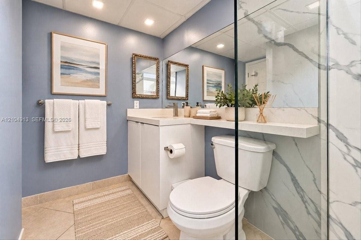 501 E Dania Beach Boulevard, #5-4A, Dania, Dania Beach, FL 33004 Bathroom featuring a vanity with integrated countertop and shelf, full-width wall mirror, recessed lighting, and shower enclosure with large-format stone-pattern tile surrounds