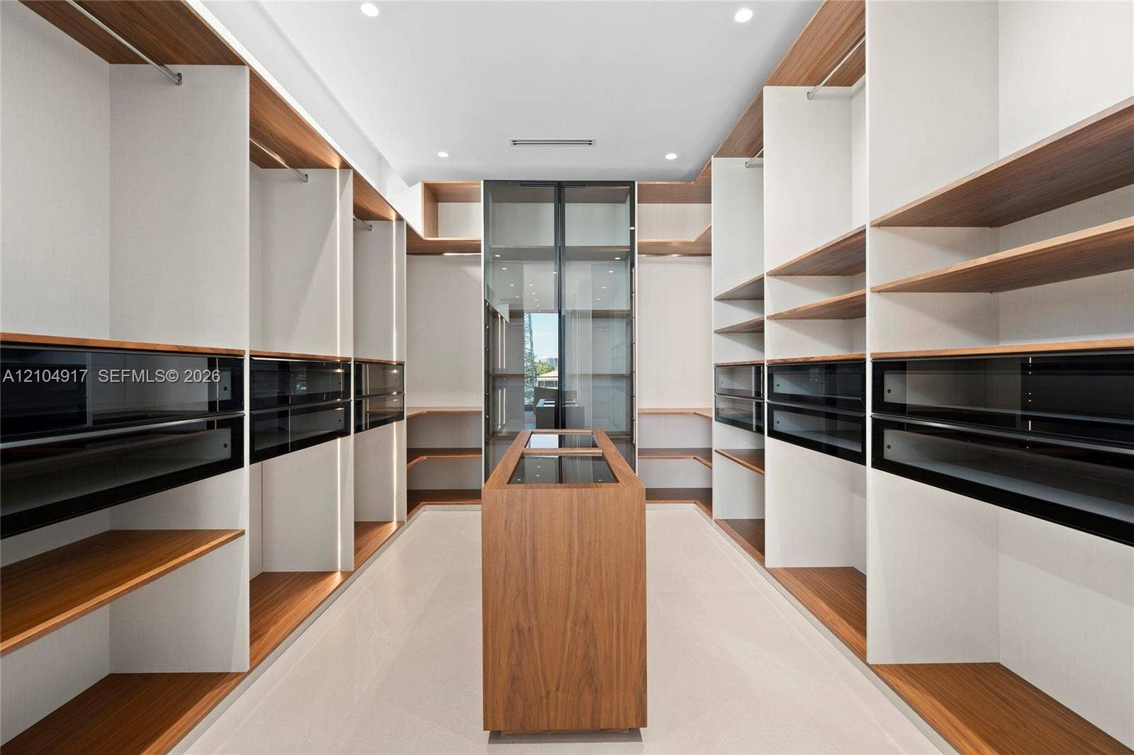 Custom built-in shelving with wood-finish accents, integrated drawers with black fronts, and a central wood-finish island