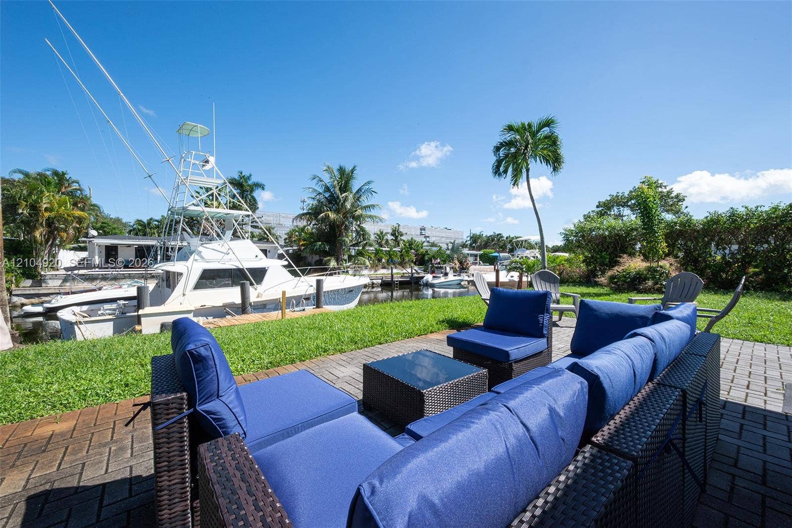 Waterfront property featuring a private boat dock, concrete paver patio, and mature palm trees