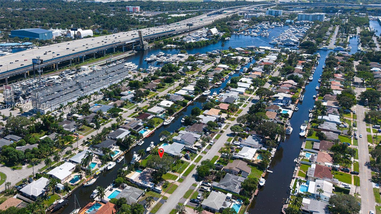 Aerial perspective of the waterfront residential property featuring direct canal access, a private dock, and mature landscaping