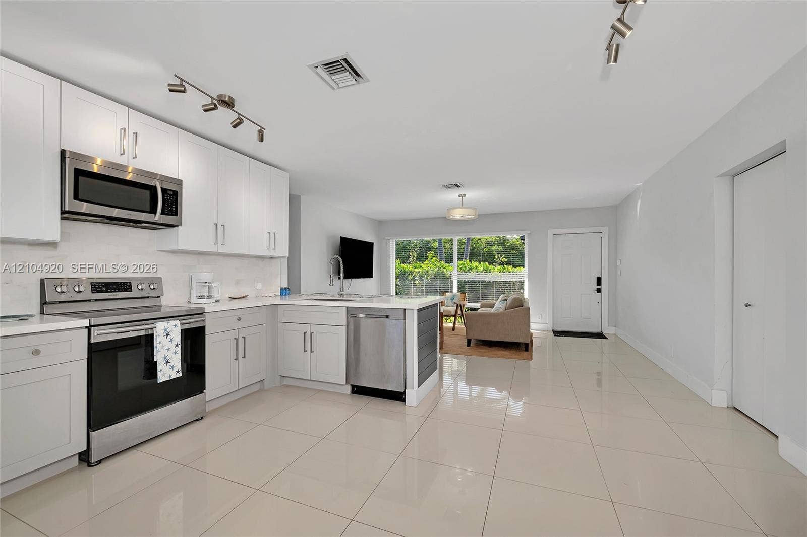 Kitchen featuring white cabinetry, stainless steel appliances, stone-finish countertops, tile flooring, and track lighting