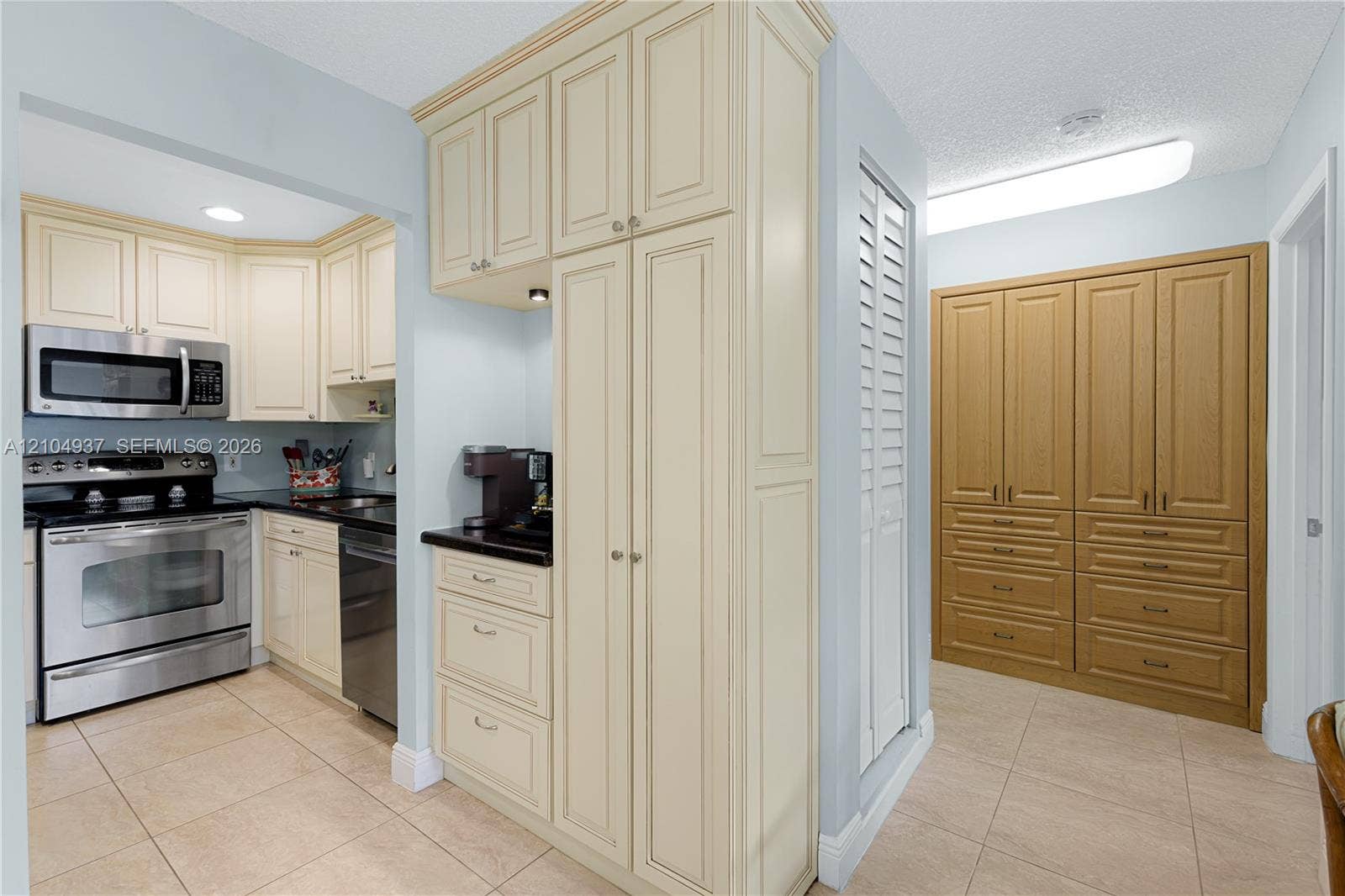 4108 NW 88th Avenue, #3, Coral Springs, FL 33065 Kitchen featuring cream-colored cabinetry, stainless steel appliances, dark stone-finish countertops, tile flooring, and integrated wood-tone storage cabinetry