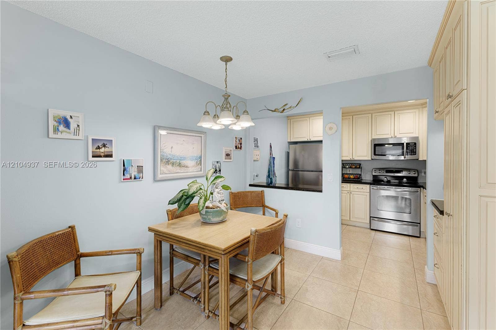 4108 NW 88th Avenue, #3, Coral Springs, FL 33065 Dining area featuring neutral tile flooring, a multi-light chandelier, and a pass-through opening to the kitchen
