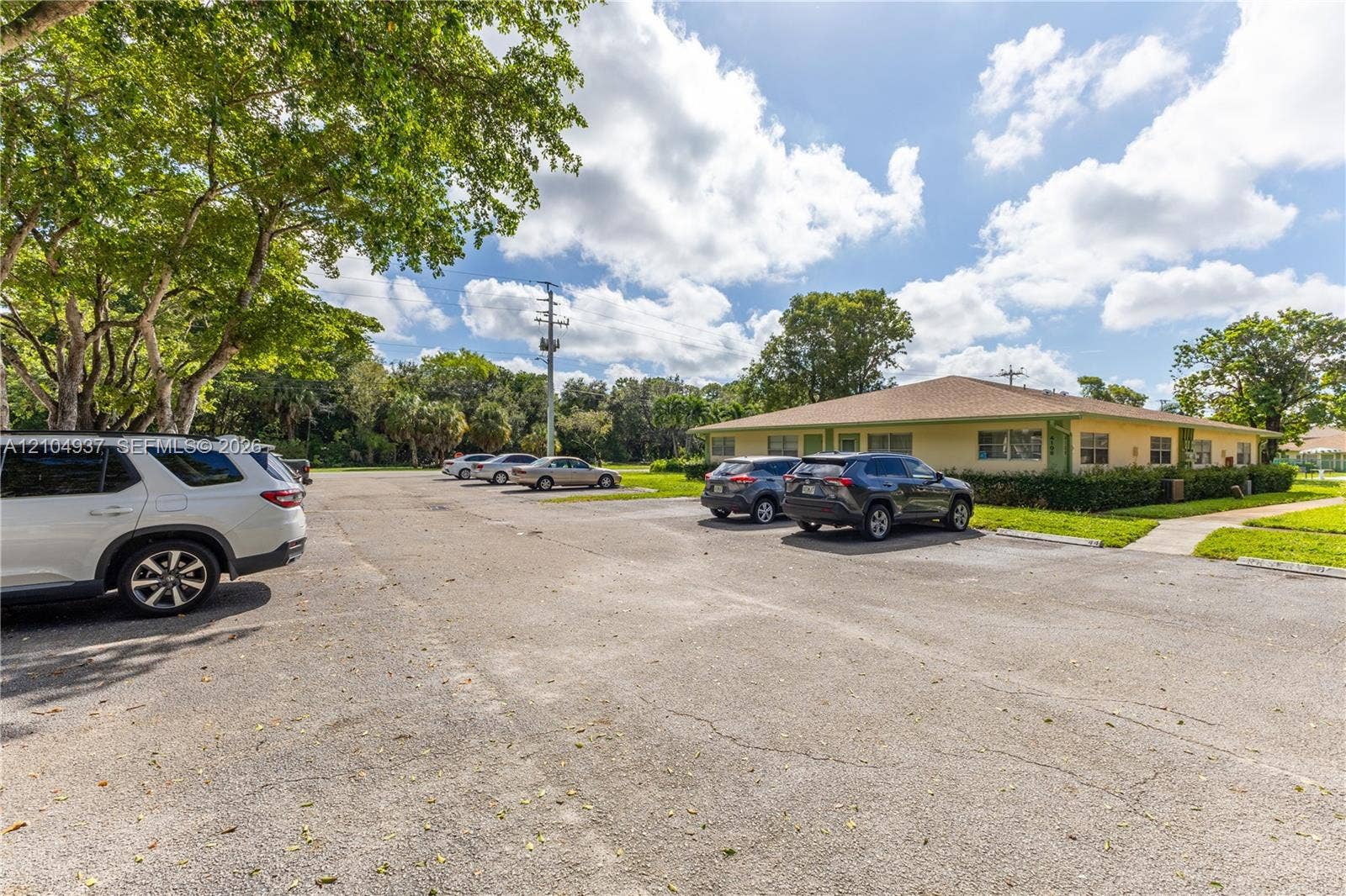 4108 NW 88th Avenue, #3, Coral Springs, FL 33065 Asphalt parking area featuring mature perimeter trees and concrete walkways