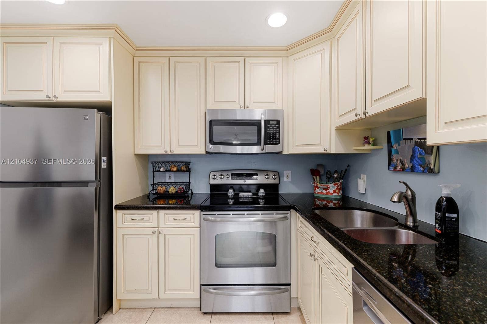 4108 NW 88th Avenue, #3, Coral Springs, FL 33065 Kitchen featuring cream-colored cabinetry, dark stone countertops, stainless steel appliances, and a dual-basin stainless steel undermount sink