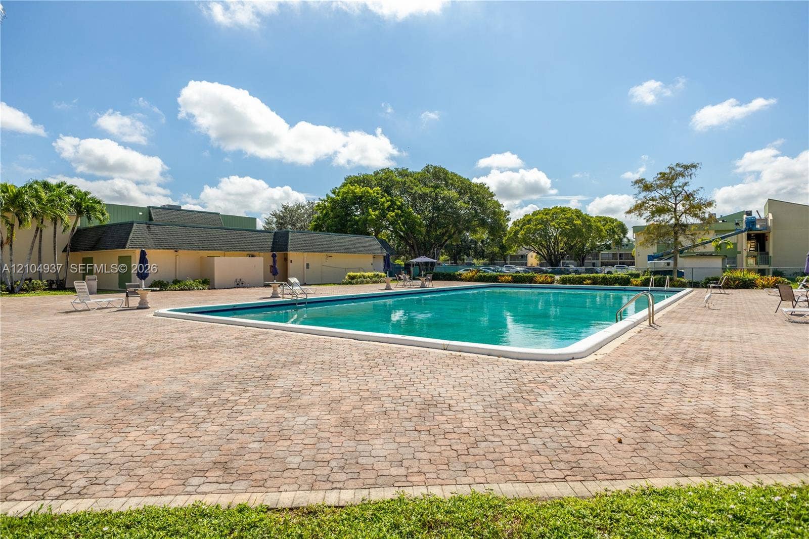 4108 NW 88th Avenue, #3, Coral Springs, FL 33065 Rectangular swimming pool featuring a brick-paver deck and surrounding mature trees