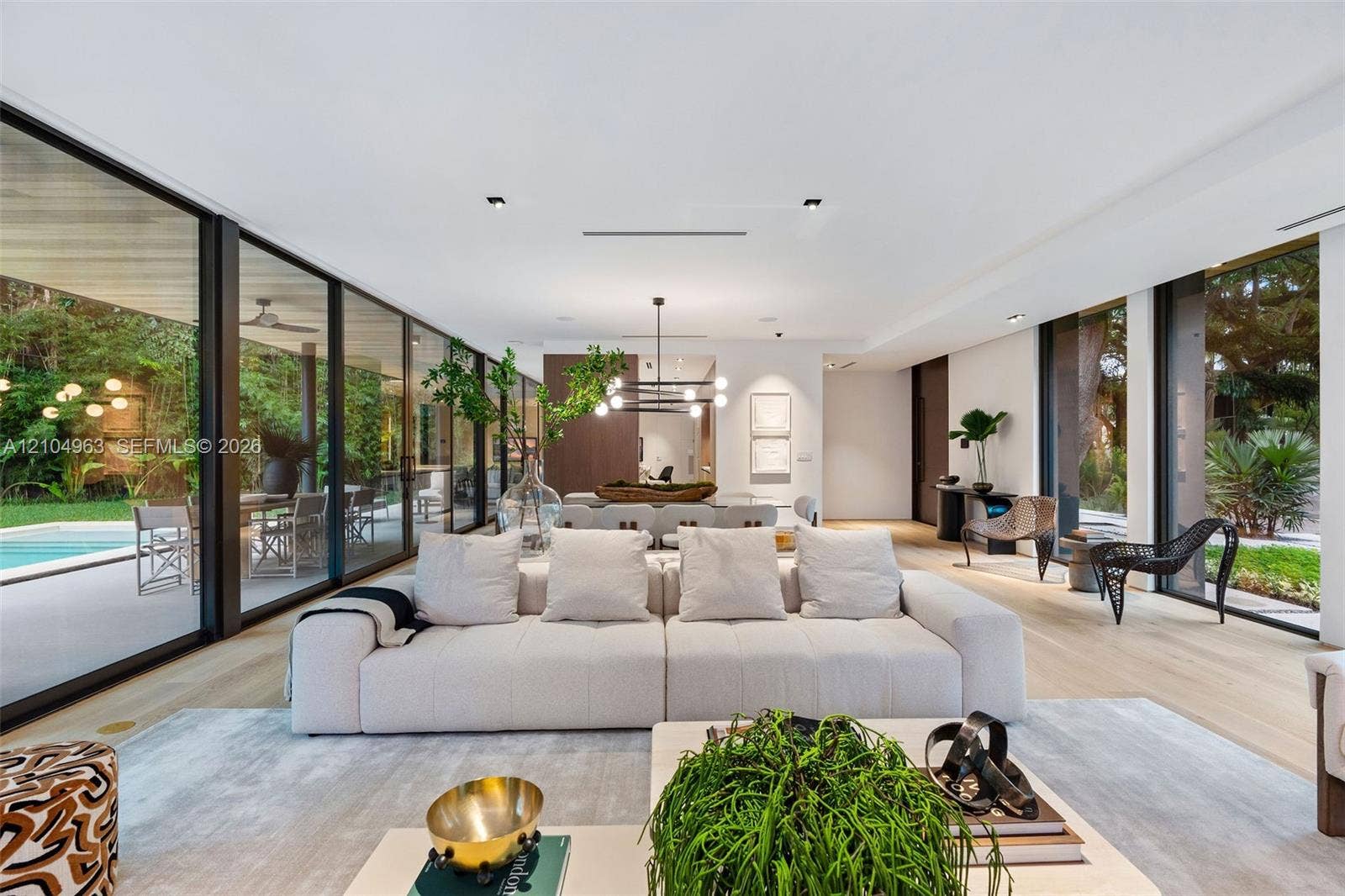 Living area featuring floor-to-ceiling glass sliding doors, wide-plank light wood-finish flooring, recessed lighting, and a modern multi-arm chandelier