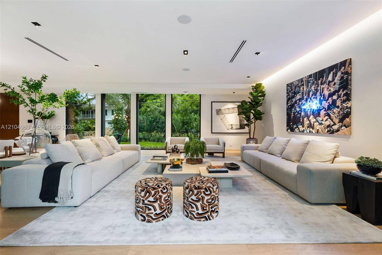 Open-concept living space featuring wood-finish flooring, recessed ceiling lighting, linear air diffusers, and expansive floor-to-ceiling windows