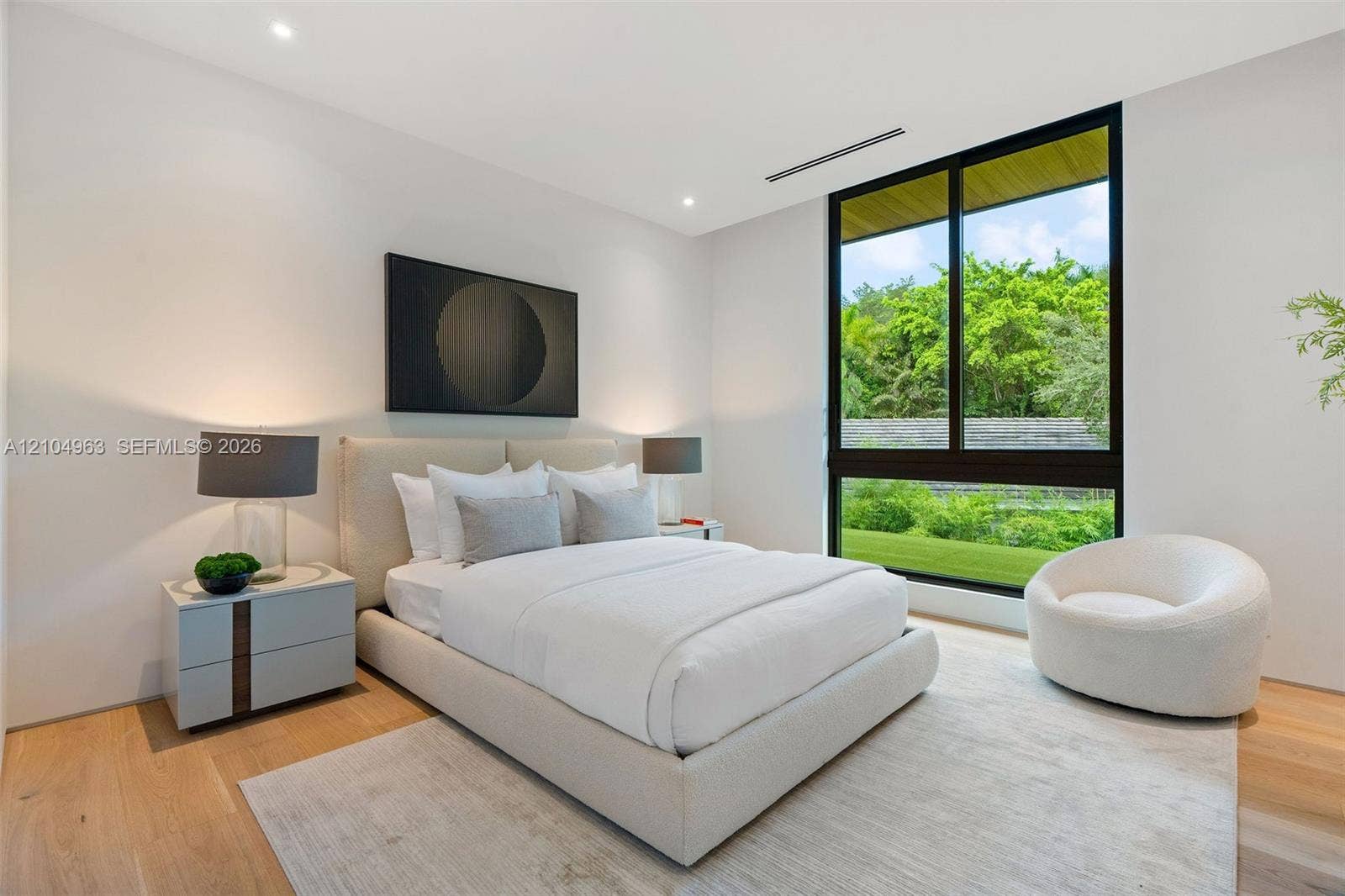 Floor-to-ceiling black-framed window, wide-plank wood-finish flooring, and recessed ceiling lighting