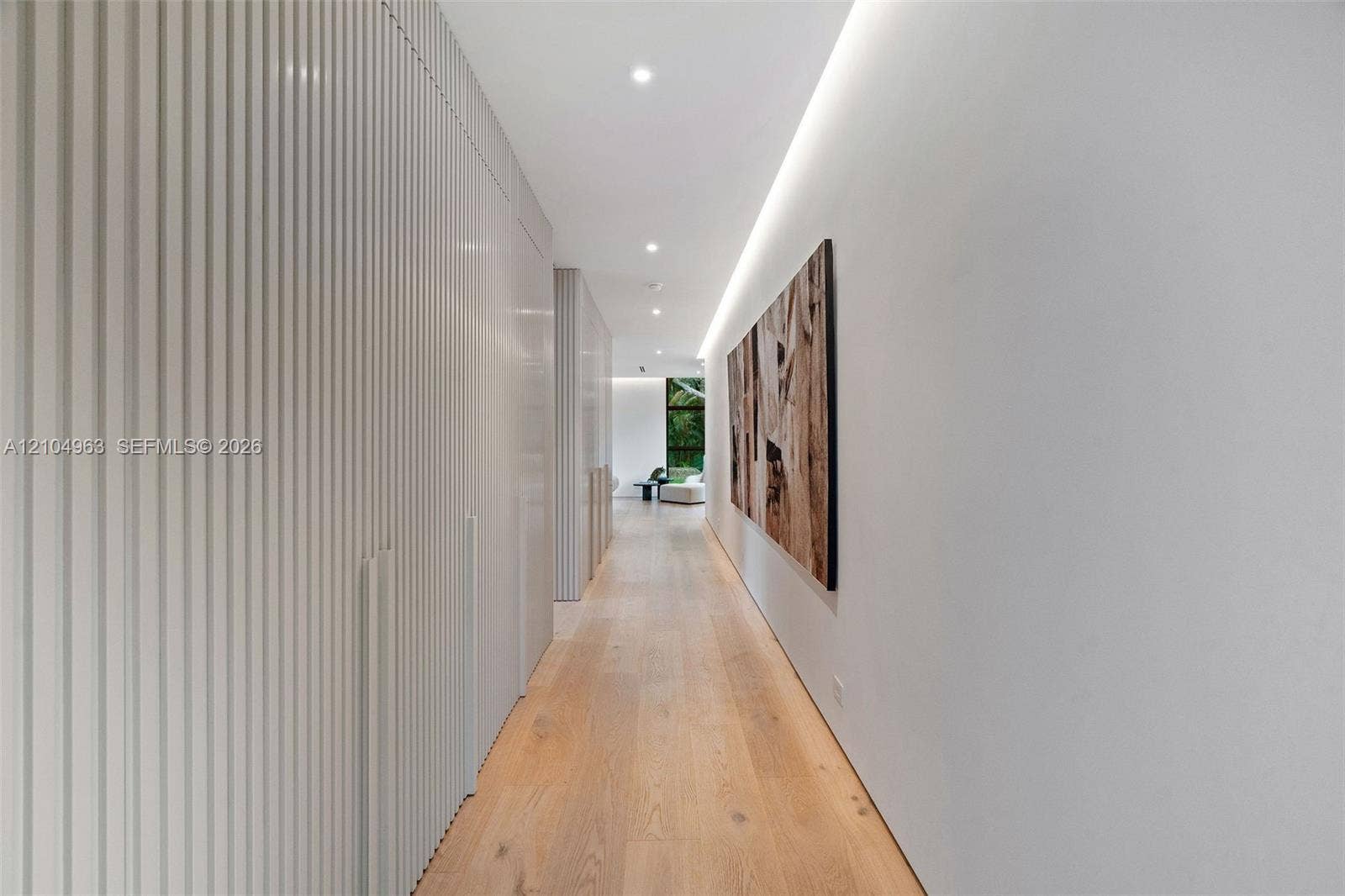 Hallway featuring floor-to-ceiling slatted built-in cabinetry, wood-finish flooring, and recessed architectural cove lighting