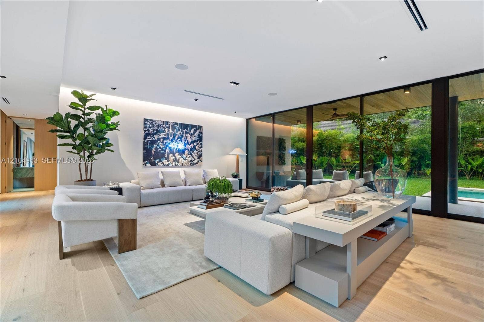 Floor-to-ceiling sliding glass walls, wood-finish flooring, recessed linear lighting, and integrated ceiling speakers