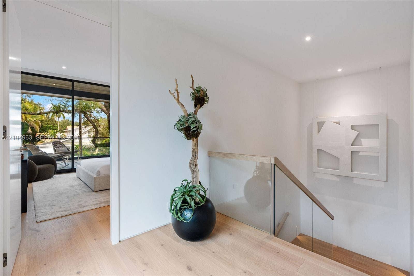 Wood-finish flooring, glass panel stair railing with a natural wood handrail, recessed ceiling lighting, and floor-to-ceiling sliding glass doors