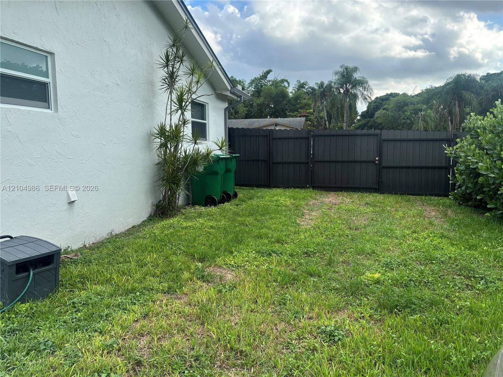 Davie, FL 33314 Rear exterior featuring a smooth stucco finish and a dark-toned vertical privacy fence