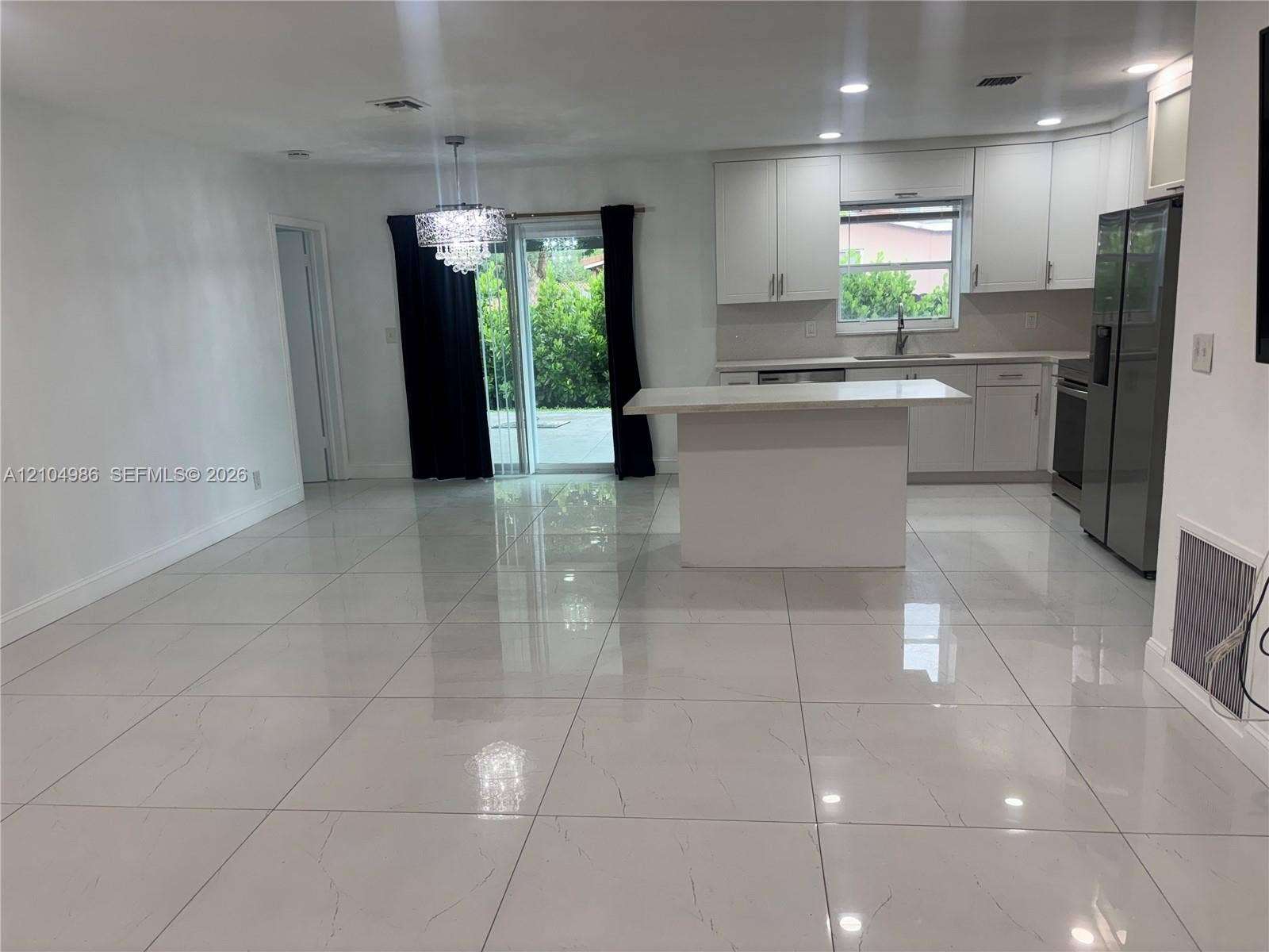Davie, FL 33314 Kitchen featuring white cabinetry, an island with a countertop, large-format tile flooring, recessed lighting, and a crystal-style chandelier