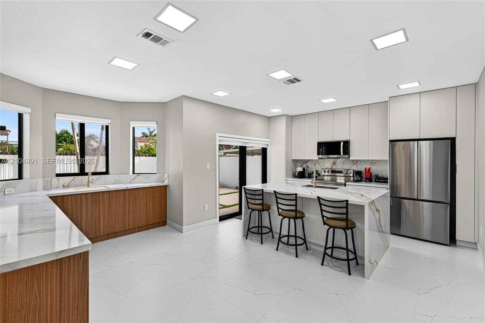 15217 SW 36th Terrace, #0, Miami, Miami, FL 33185 Modern kitchen featuring flat-panel cabinetry, stone-finish countertops with waterfall edge, stainless steel appliances, and large-format tile flooring
