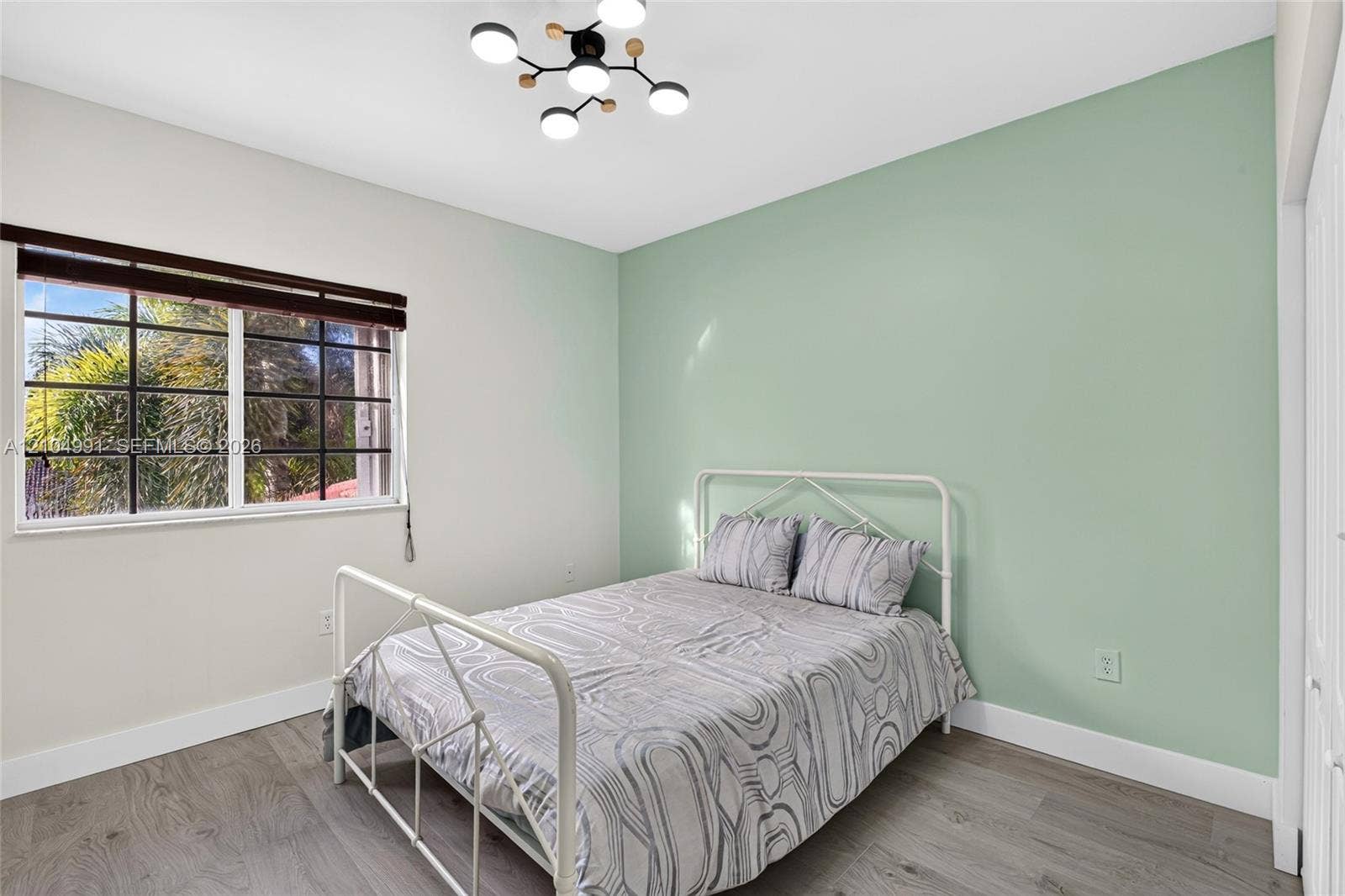 15217 SW 36th Terrace, #0, Miami, Miami, FL 33185 Room featuring wood-finish flooring, a contemporary multi-light fixture, an accent wall, and a multi-pane window with a horizontal blind