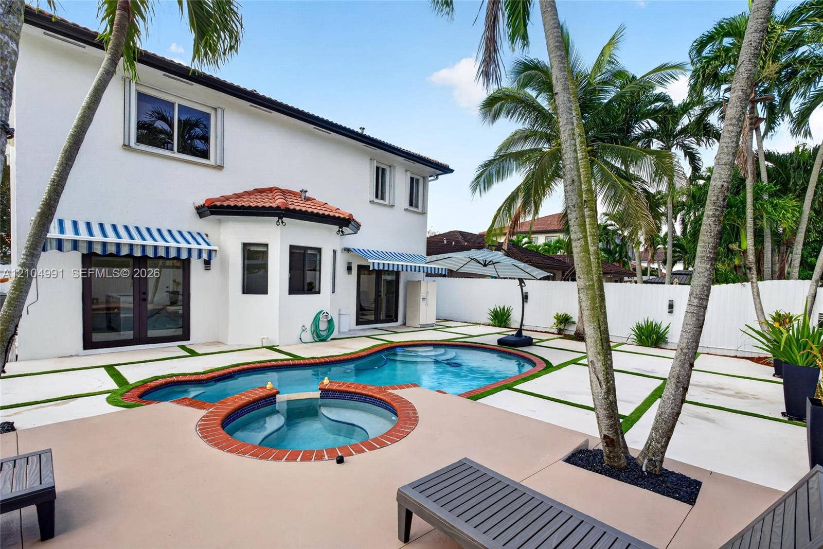 15217 SW 36th Terrace, #0, Miami, Miami, FL 33185 Exterior rear featuring a stucco facade, swimming pool with an attached spa, paver patio with turf inlays, and striped retractable awnings