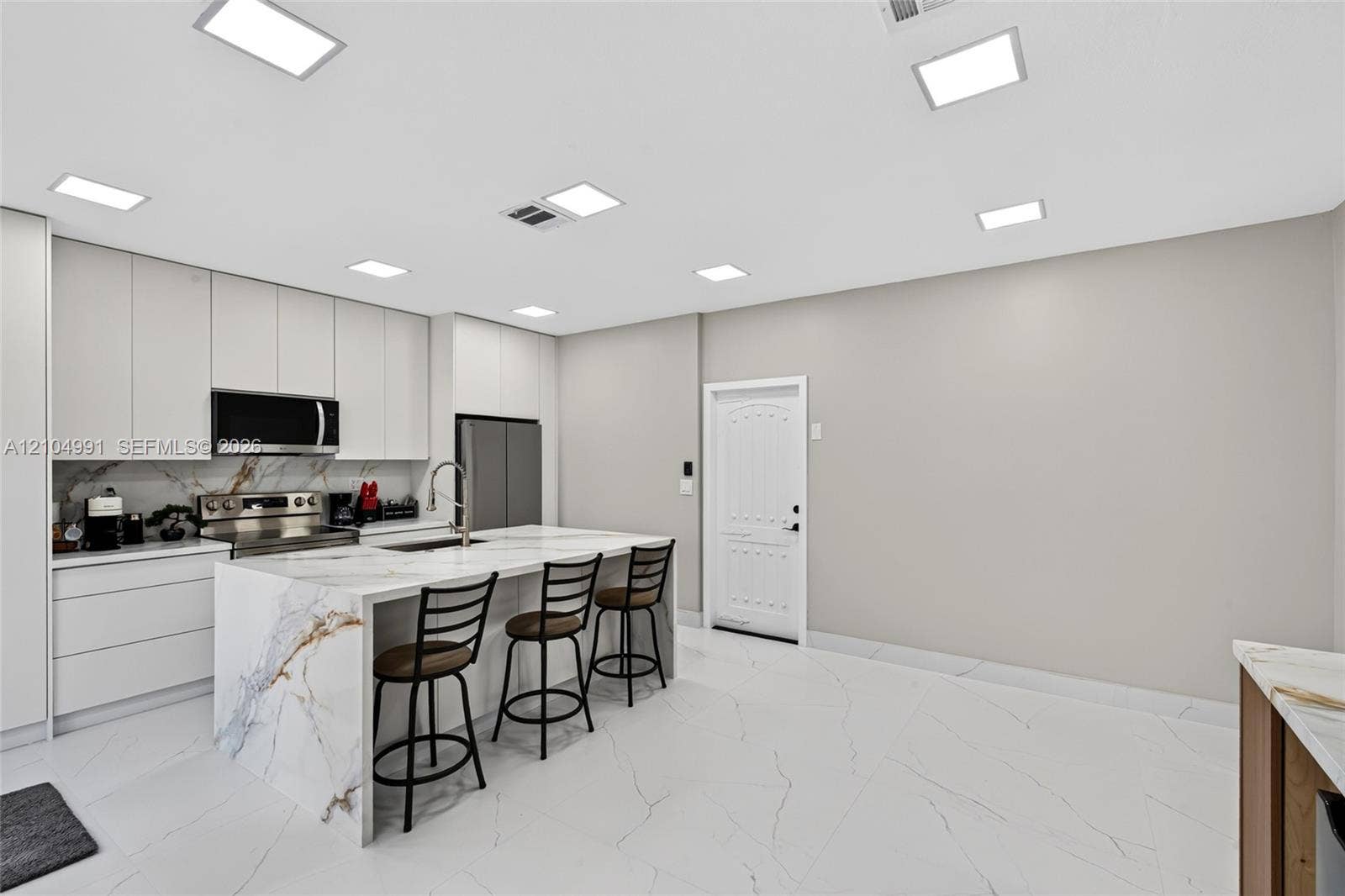 15217 SW 36th Terrace, #0, Miami, Miami, FL 33185 Kitchen featuring floor-to-ceiling cabinetry, a waterfall-edge island with stone-finish countertops, large-format tile flooring, and integrated square LED ceiling lighting