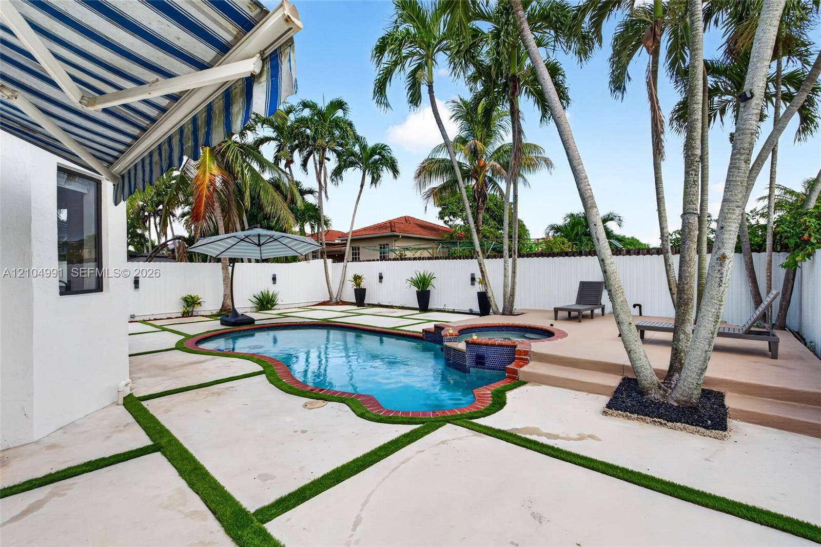 15217 SW 36th Terrace, #0, Miami, Miami, FL 33185 In-ground pool with integrated spa, paver patio with turf detailing, retractable fabric awning, and perimeter privacy fencing