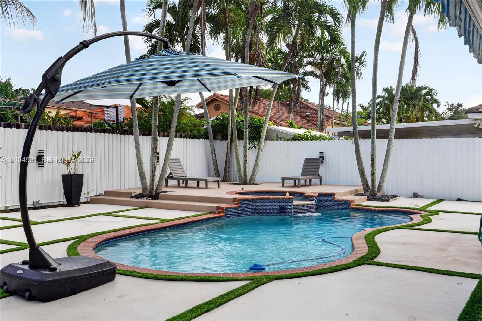 15217 SW 36th Terrace, #0, Miami, Miami, FL 33185 Backyard featuring a custom-shaped swimming pool with a tiered tile spa, concrete paver patio with turf detailing, and a perimeter privacy fence