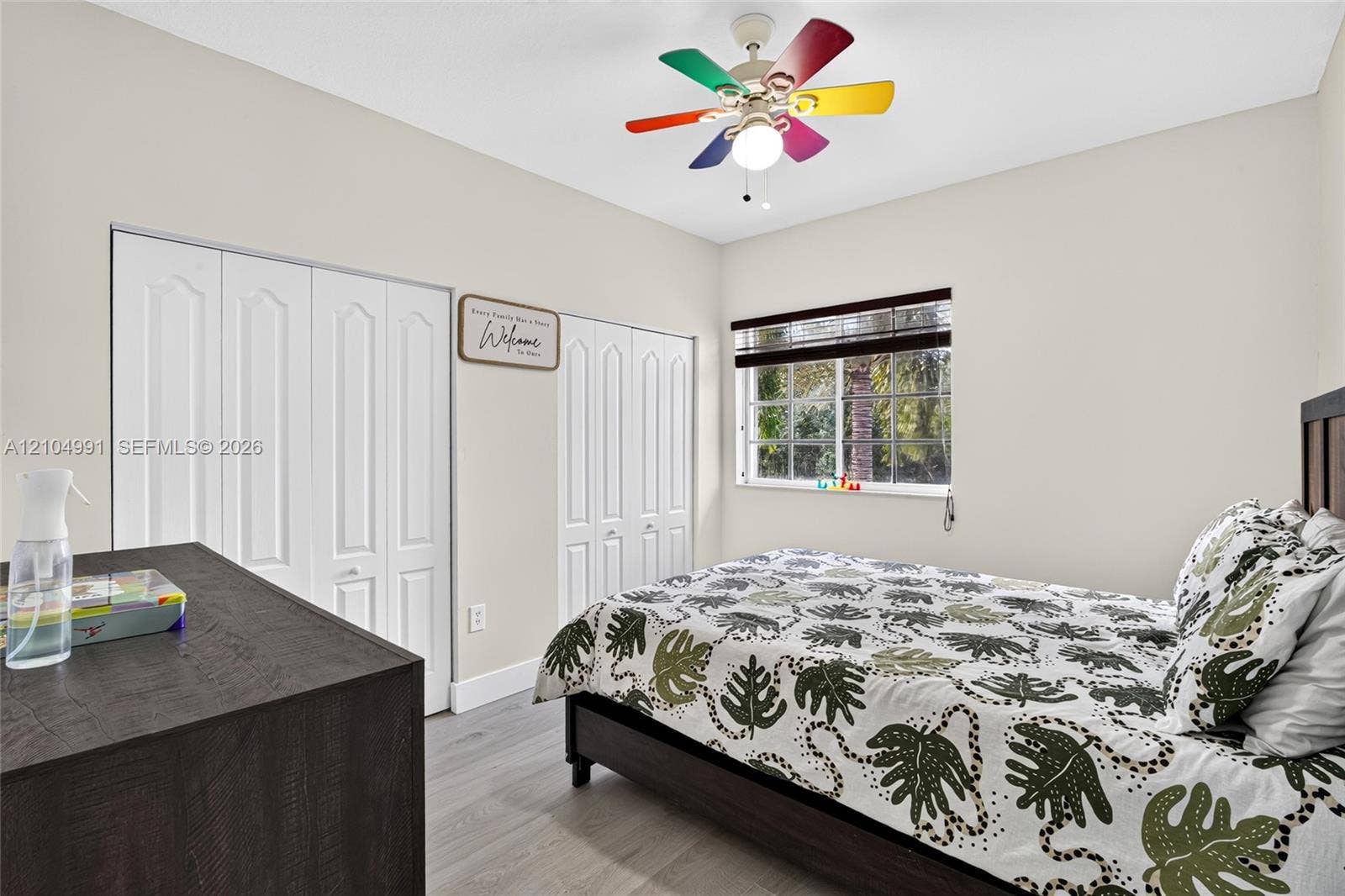 15217 SW 36th Terrace, #0, Miami, Miami, FL 33185 Neutral-toned walls, wood-finish flooring, dual bi-fold closet doors, and a multi-colored ceiling fan with integrated light fixture