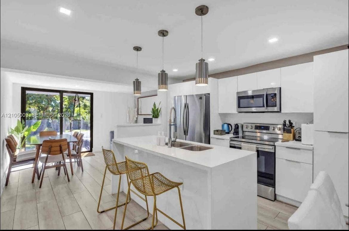 254 NW 51st Street, Miami, Miami, FL 33127 Contemporary kitchen featuring white cabinetry, stainless steel appliances, and a central island with an integrated sink