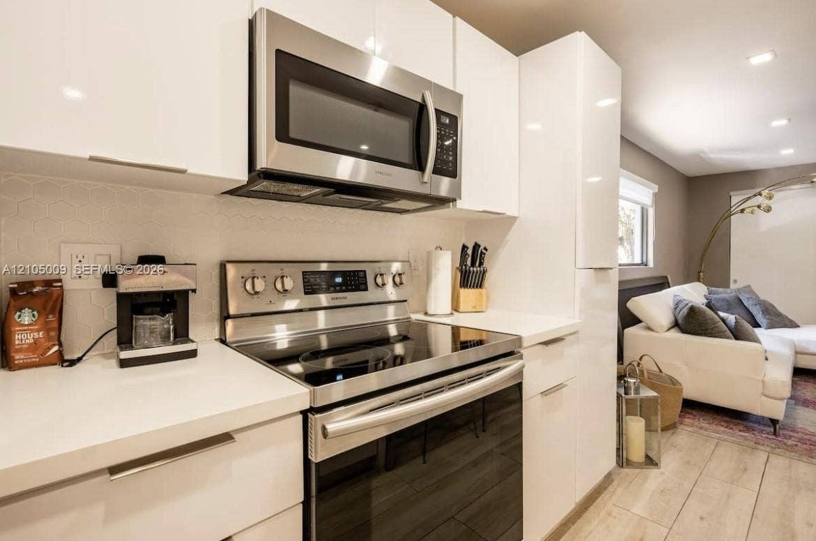 254 NW 51st Street, Miami, Miami, FL 33127 Kitchen featuring stainless steel appliances, white flat-panel cabinetry, white countertops, and a white hexagonal tile backsplash
