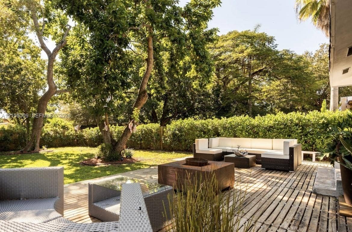 254 NW 51st Street, Miami, Miami, FL 33127 Expansive backyard featuring a manicured lawn, mature trees, and a spacious wood-slat patio