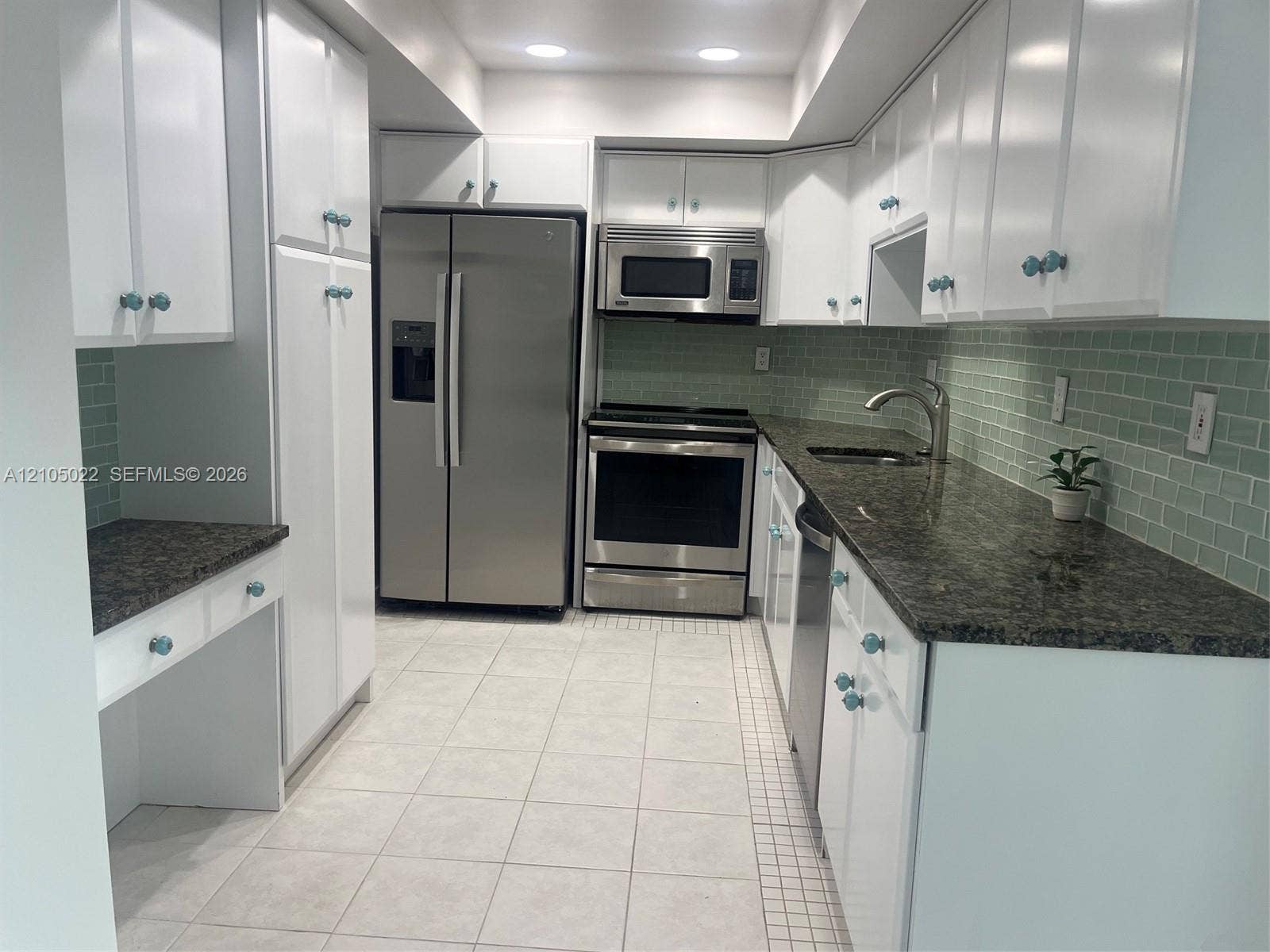 500 Bayview Drive, #1520, Sunny Isles Beach, Sunny Isles Beach, FL 33160 White cabinetry, dark stone countertops, stainless steel appliances, light tile flooring, and a green subway tile backsplash