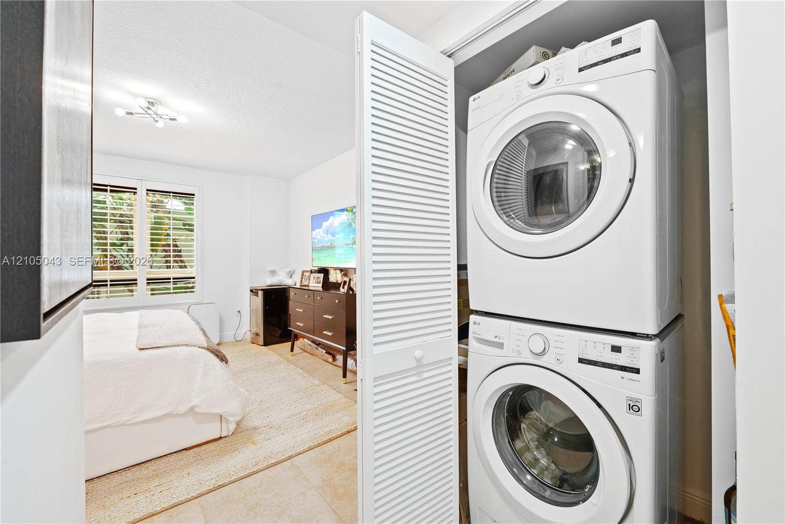 3540 Main Highway, #207, Miami, FL 33133 Stackable laundry unit housed within a closet featuring white louvered doors