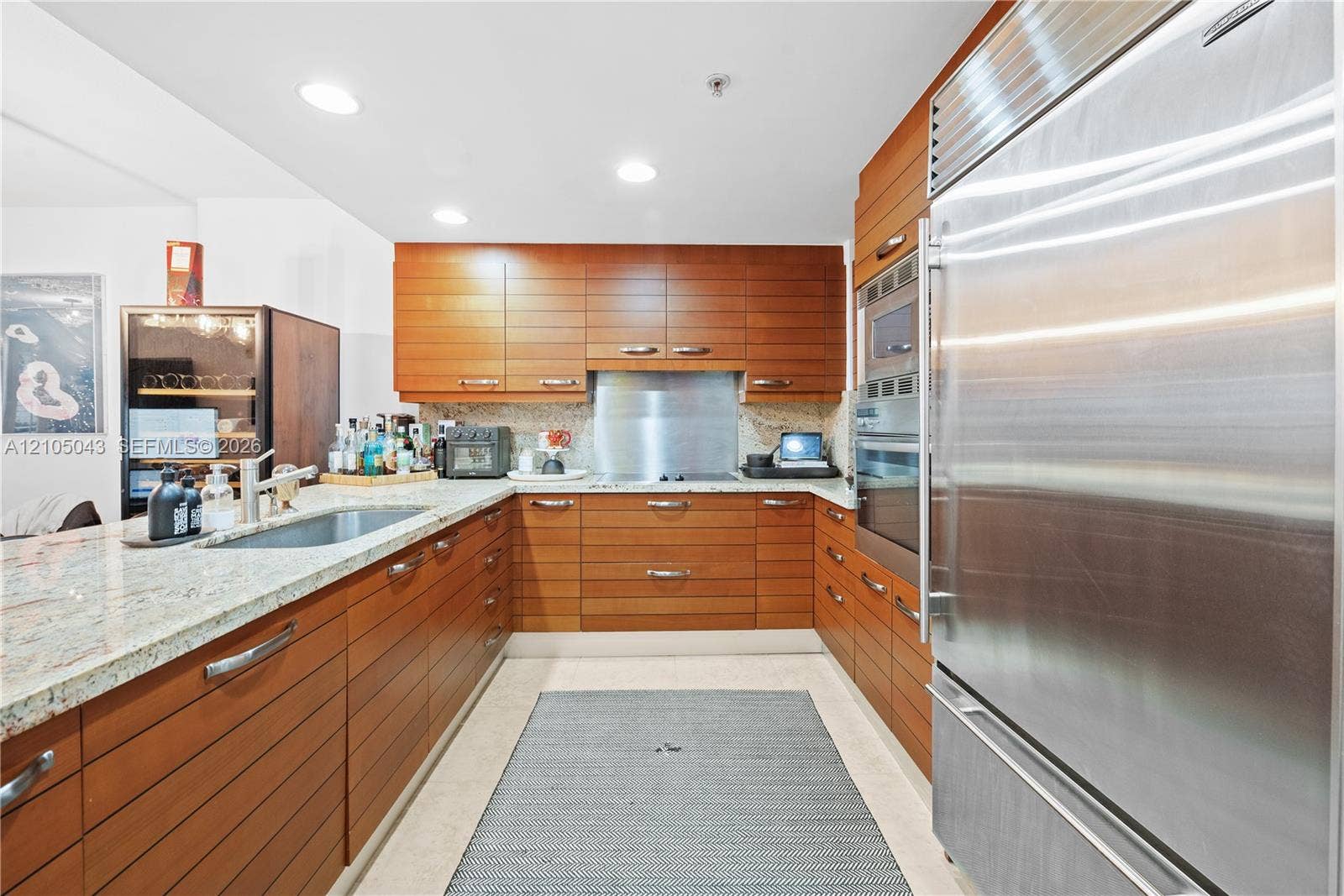 3540 Main Highway, #207, Miami, FL 33133 Neutral-toned tile flooring, recessed ceiling lighting, and double glass doors featuring white louvered shutters opening to a private balcony