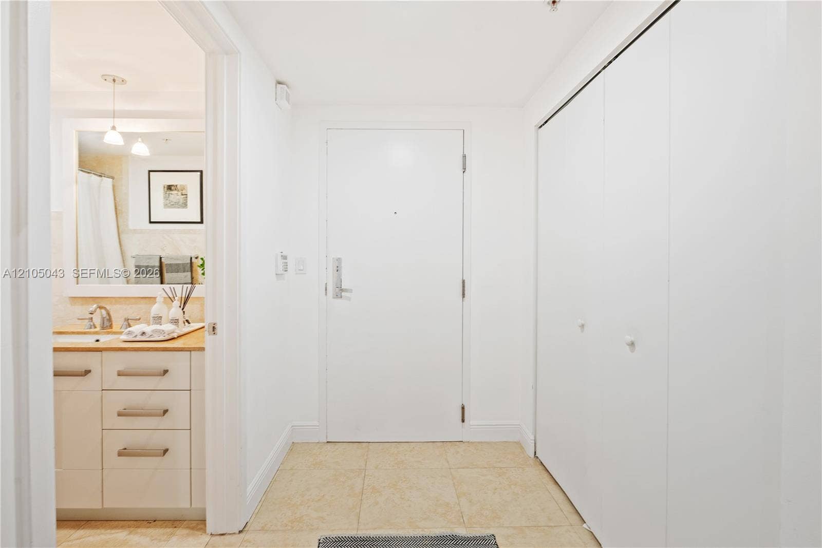 3540 Main Highway, #207, Miami, FL 33133 Double vanity featuring cabinetry with brushed metal hardware, dual under-mount sinks, integrated stone-finish countertop, and large wall-mounted mirror with integrated lighting