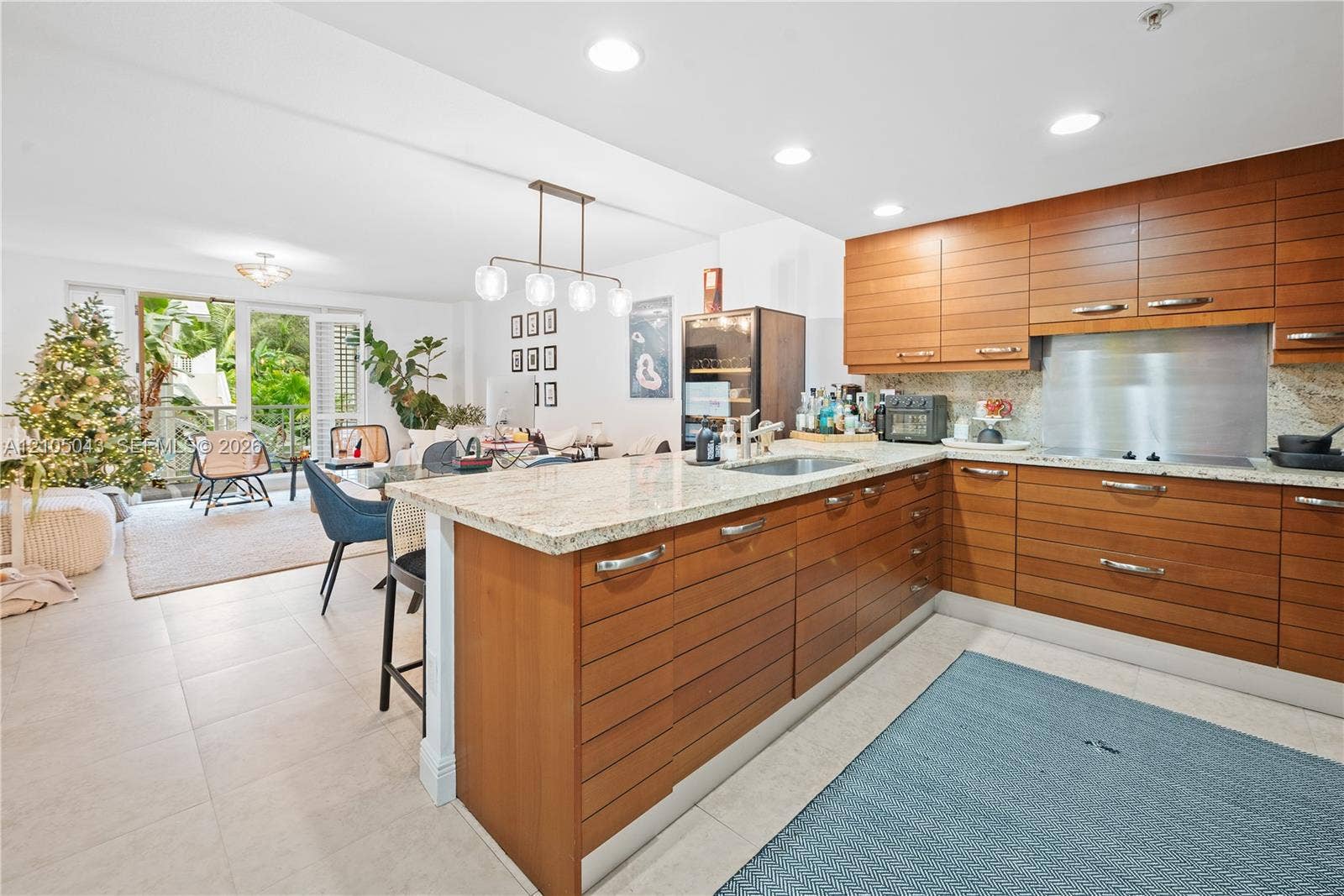 3540 Main Highway, #207, Miami, FL 33133 Living area featuring neutral tile flooring, a woven semi-flush mount light fixture, and floor-to-ceiling glass doors opening to a covered balcony with metal railing