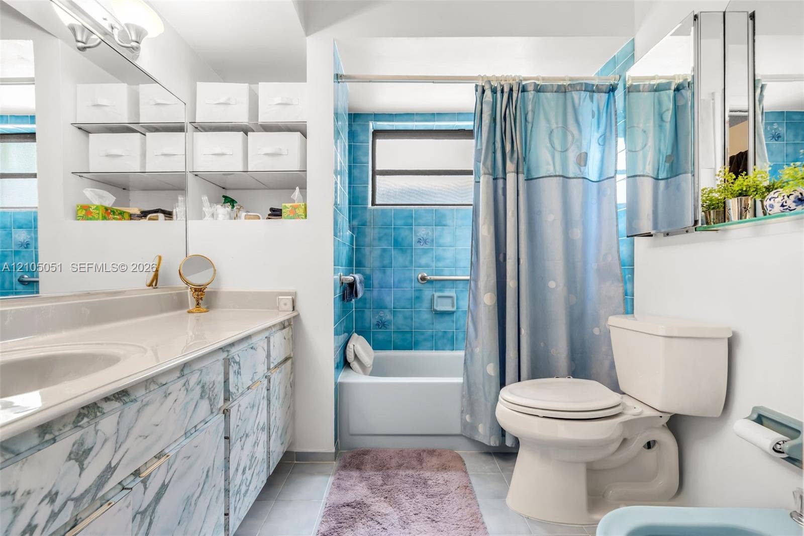 461 SW 89th Court, Miami, FL 33174 Bathroom featuring a vanity with integrated sink and stone-patterned cabinetry, blue tile tub surround, inset shelving, and a wall-mounted mirrored medicine cabinet