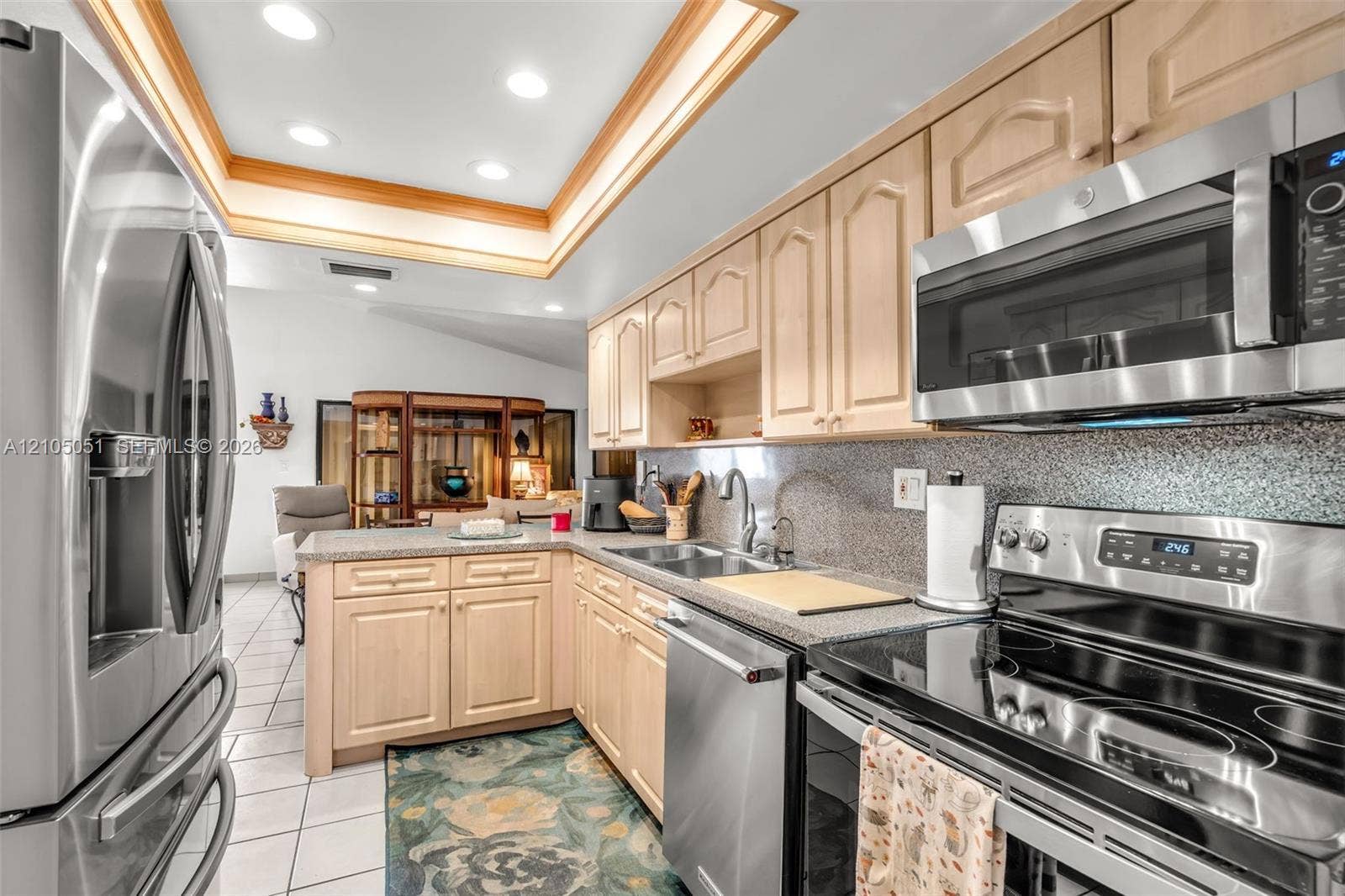 461 SW 89th Court, Miami, FL 33174 Kitchen featuring light wood cabinetry, stone countertops, stainless steel appliances, and a recessed tray ceiling with integrated lighting