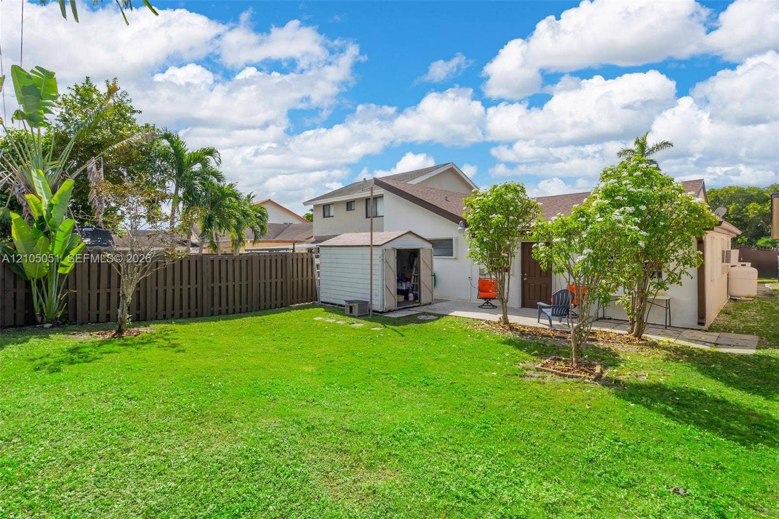 461 SW 89th Court, Miami, FL 33174 Backyard featuring a manicured lawn, perimeter wood privacy fencing, a concrete patio, and mature landscaping