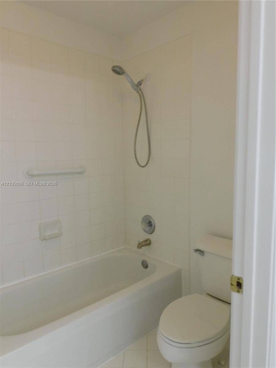 16729 Amber Lake, Weston, FL 33331 White tiled shower surround with a handheld shower head, tub, and toilet