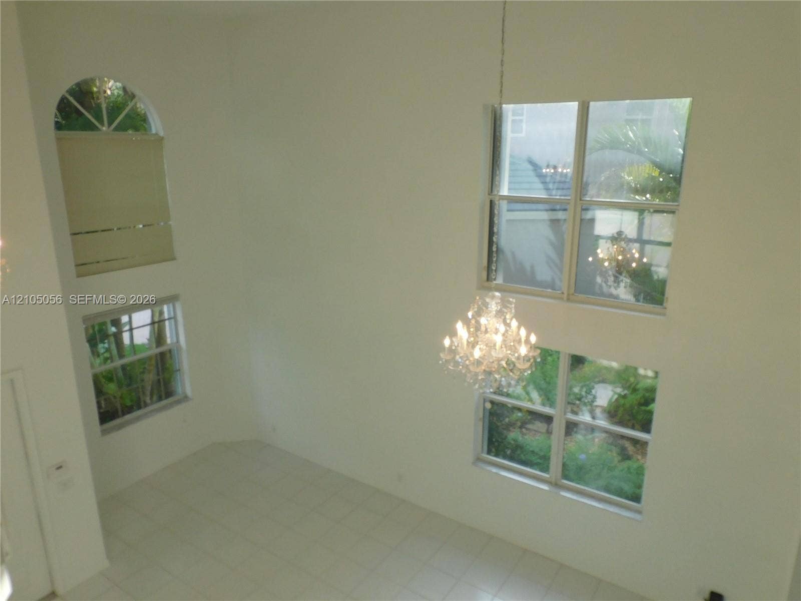16729 Amber Lake, Weston, FL 33331 Double-height ceiling with a crystal chandelier, multiple large windows, an arched window, and tile flooring