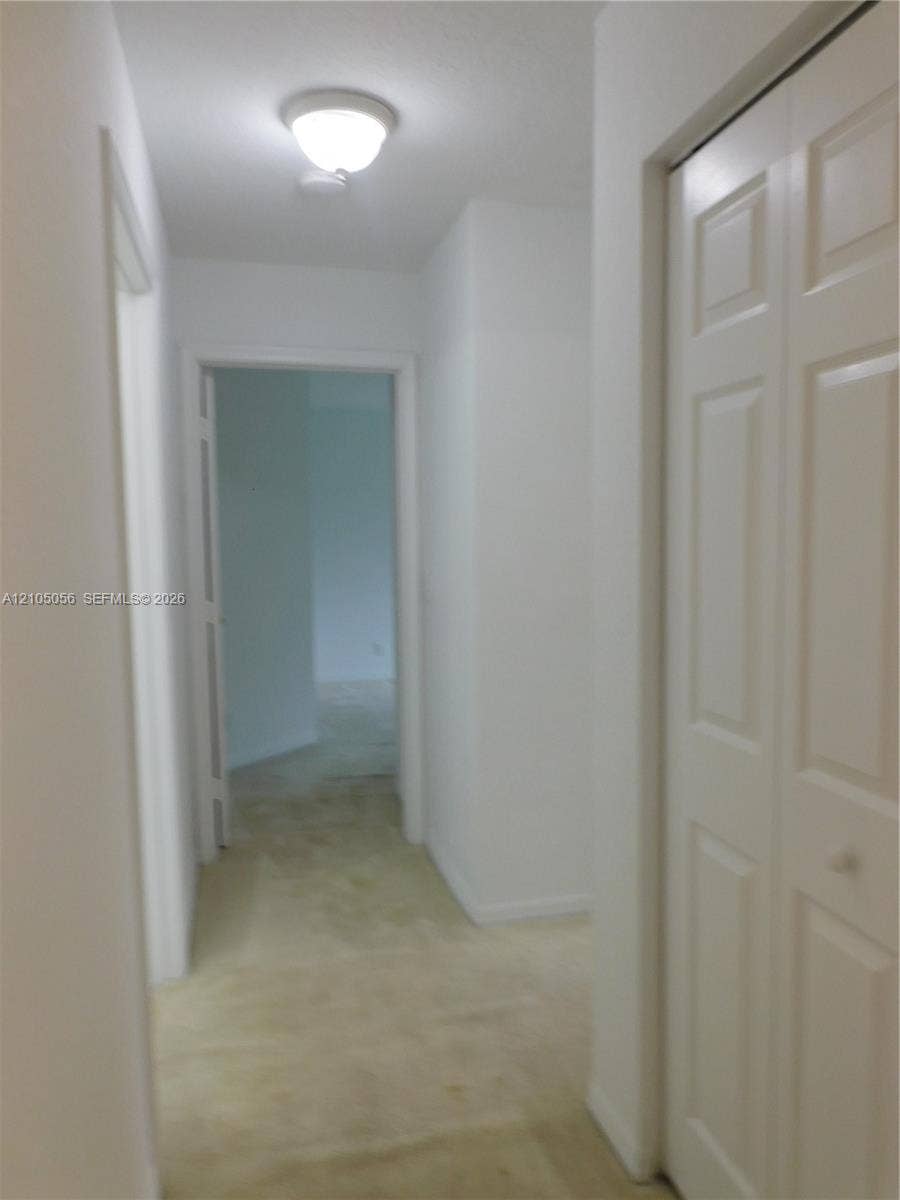 16729 Amber Lake, Weston, FL 33331 Hallway featuring light-toned carpeting, white walls, and a flush-mount ceiling light
