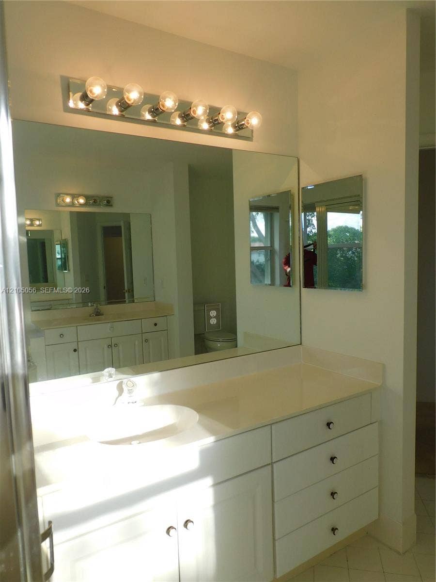16729 Amber Lake, Weston, FL 33331 Dual vanity with white cabinetry, integrated sinks, light-toned countertop, and chrome vanity lighting