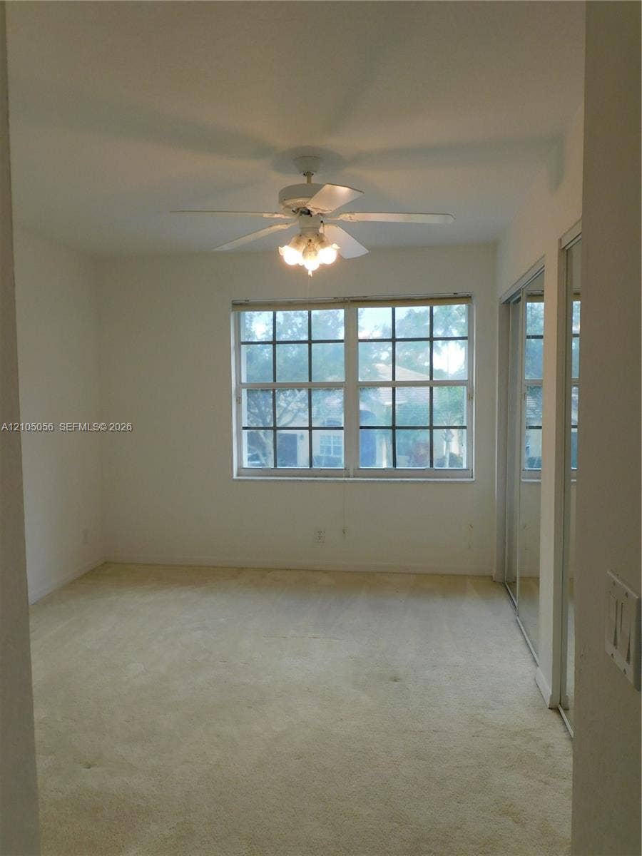16729 Amber Lake, Weston, FL 33331 Window with grid-pane detailing, ceiling fan with integrated lighting, wall-to-wall carpeting, and mirrored sliding closet doors