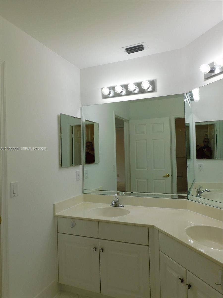 16729 Amber Lake, Weston, FL 33331 Dual vanity with integrated sinks, ample countertop space, contemporary wall-mounted light fixtures, and mirrored medicine cabinets