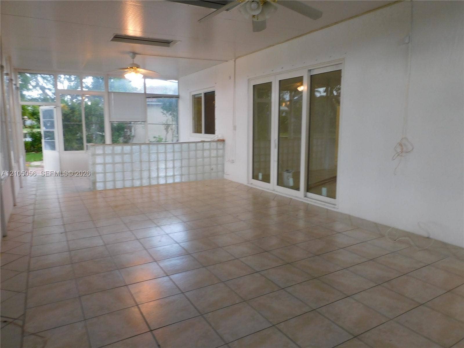 16729 Amber Lake, Weston, FL 33331 Enclosed patio with tile flooring, glass block partition, ceiling fans, and sliding glass doors