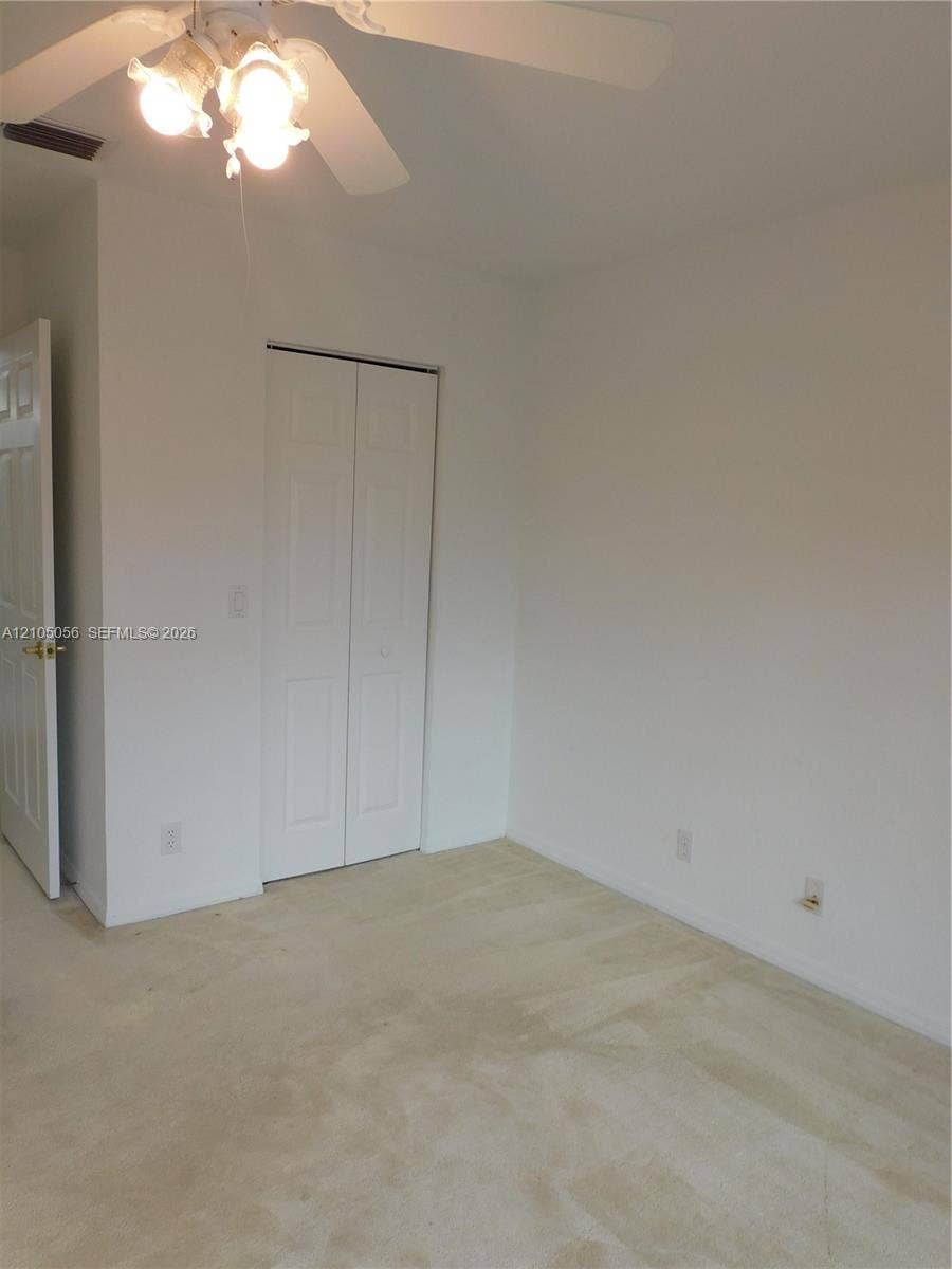 16729 Amber Lake, Weston, FL 33331 Recessed closet with bifold doors, neutral-toned wall-to-wall carpeting, and a ceiling fan with integrated lighting