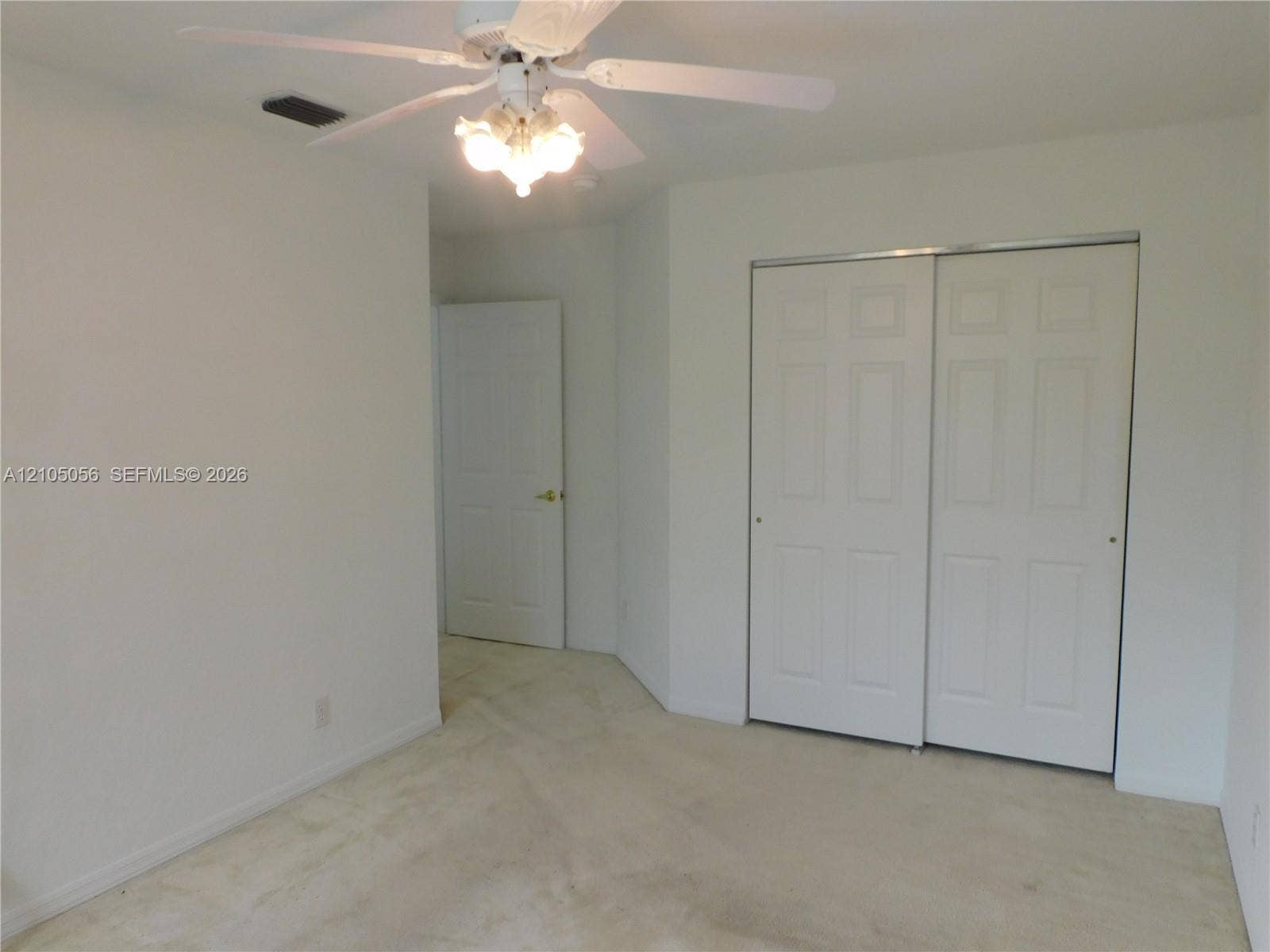16729 Amber Lake, Weston, FL 33331 Neutral carpet flooring, white walls, white ceiling fan with integrated lighting, and white bi-fold closet doors