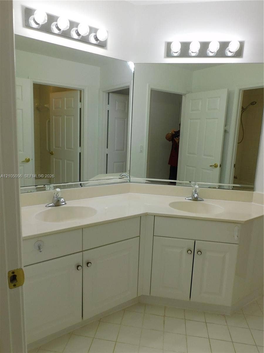 16729 Amber Lake, Weston, FL 33331 Dual vanity with integrated sinks, white cabinetry, and a large wall-mounted mirror