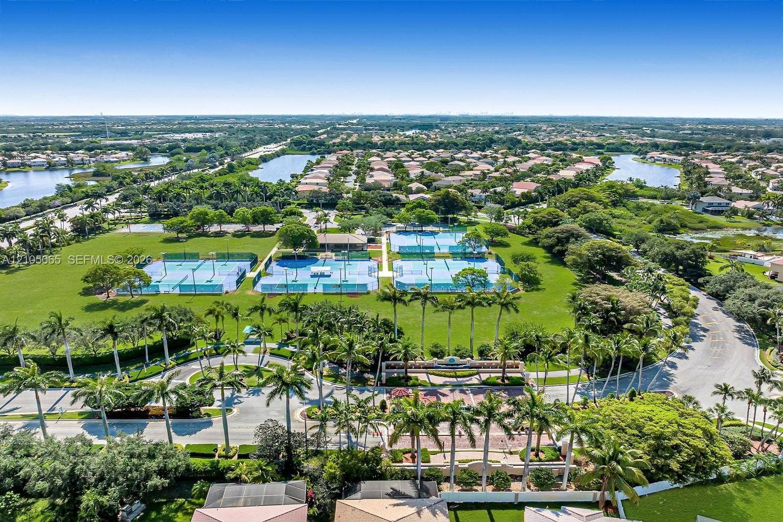 17621 SW 4th Court, Pembroke Pines, FL 33029 Aerial perspective featuring multiple tennis courts, manicured green space, mature palm trees, and community water features